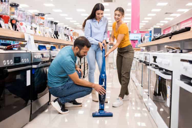 young couple gets assistance buying vacuum cleaner in appliance store